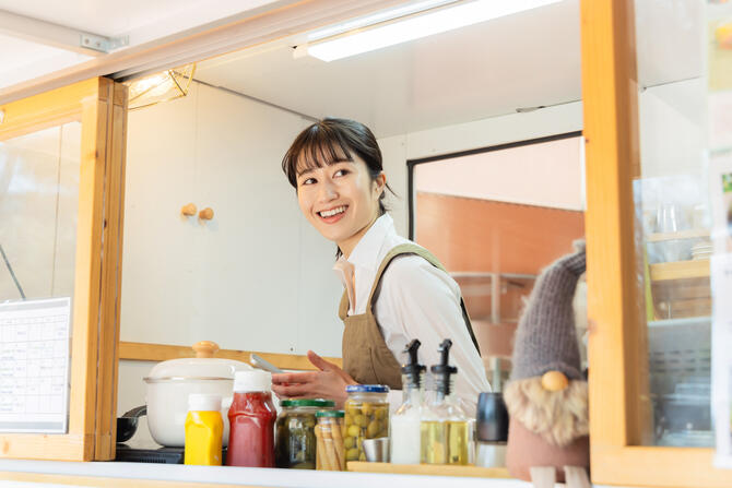 テイクアウト専門店のキッチンで働く店員の女性